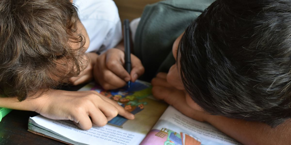 two young boys reading book together