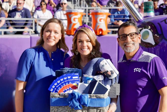 teacher of the year kristy butler smiling with gift basket presented by EECU representative and Dean Frank Hernandez