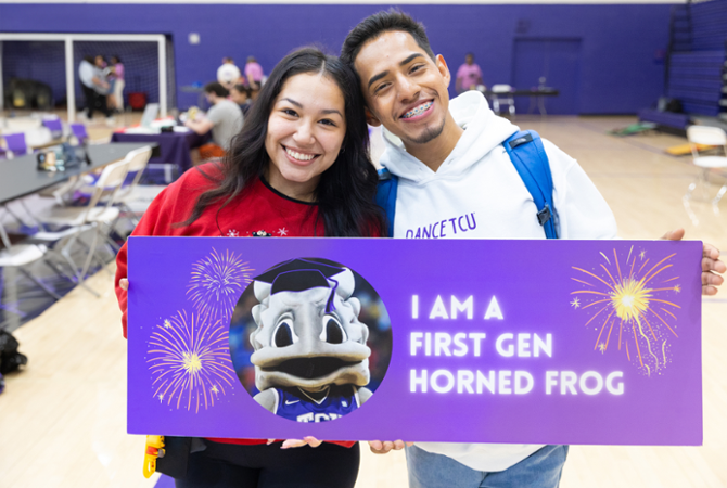 male and female student smiling with "I am a first gen horned frog" sign